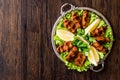 Turkish Food Cig Kofte with lemon, lettuce and parsley on silver tray.