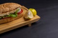 Turkish food sandwich balik Ekmek with grilled mackerel, tomatoes, onions and lettuce served with lemon closeup on the table. Royalty Free Stock Photo