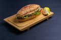 Turkish food sandwich balik Ekmek with grilled mackerel, tomatoes, onions and lettuce served with lemon closeup on the table. Royalty Free Stock Photo