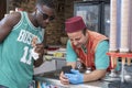 Turkish ice cream seller and black guy tourist watching mobile phone in old town street of Bodrum, Turkey