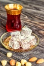 Turkish joys with different nuts is a glass of tea and a spoon. Eastern sweets. Traditional Turkish delight Rahat lokum on a Royalty Free Stock Photo