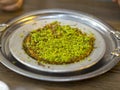 Turkish kunefe dessert in special serving dish with green pistachio