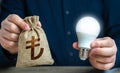 Turkish lira money bag and burning idea light bulb in the hands of a man. Royalty Free Stock Photo