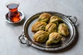 Turkish Midye Baklava Mussel Shape Baklawa with green pistachio Powder, Butter Cream and Traditional Tea in Silver Tray.