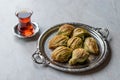 Turkish Midye Baklava Mussel Shape Baklawa with green pistachio Powder, Butter Cream and Traditional Tea in Silver Tray.