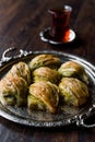 Turkish Midye Baklava Mussel Shape Baklawa with green pistachio Powder, Butter Cream and Traditional Tea in Silver Tray.