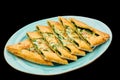 Turkish pizza pide with spinach and cheese lies on a plate on a black isolated background Royalty Free Stock Photo