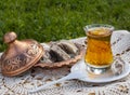 Turkish tea in a glass Cup and marble halva on a table with a handmade tablecloth and candy maker on a Sunny day Royalty Free Stock Photo
