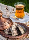 Turkish tea in a glass Cup and marble halva on a table with a handmade tablecloth and candy maker on a Sunny day Royalty Free Stock Photo