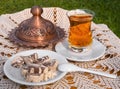 Turkish tea in a glass Cup and marble halva on a table with a handmade tablecloth and candy  maker on a Sunny day Royalty Free Stock Photo