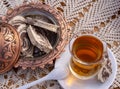 Turkish tea in a glass Cup and marble halva on a table with a handmade tablecloth and candy maker on a Sunny day Royalty Free Stock Photo