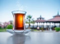 Turkish tea served in tulip-shaped glass on a small saucer blurred nature background. Summer holiday background