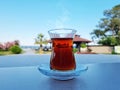 Turkish tea served in tulip-shaped glass on a small saucer blurred nature background. Summer holiday background