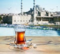Turkish tea served in tulip-shaped glass on a small saucer blurred old town and sea at the background
