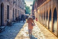 Turkish woman walking down cobblestone narrow street with benches near old traditional buildings