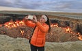 Turkmenistan, Darvaza - March 21, 2019: Girl makes selfie on the background of the burning crater