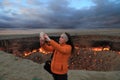 Turkmenistan, Darvaza - March 21, 2019: Girl makes selfie on the background of the burning crater