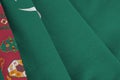 Turkmenistan flag with big folds waving close up under the studio light indoors. The official symbols and colors in