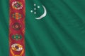 Turkmenistan flag with big folds waving close up under the studio light indoors. The official symbols and colors in