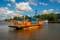 City seascape view of a small open passenger ferry with people and bicycles crossing a canal.