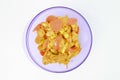 Turmeric chicken with carrots, corns and tomatoes in a purple bowl over white background Royalty Free Stock Photo