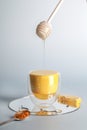 Turmeric, golden milk with powder on spoon , honey flowing from stick and lemon on blue background