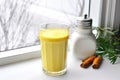 turmeric latte near windowsill with scattered turmeric powder