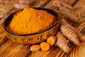 Turmeric powder in a asian bowl and turmeric roots in close up