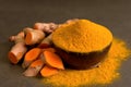 Turmeric powder in a black wooden bowl and fresh turmeric (curcumin) on black background Royalty Free Stock Photo