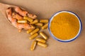 the turmeric powder and capsule and roots curcumin on brown paper