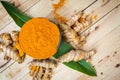 Turmeric powder and fresh turmeric Curcuma in black bowls on old wooden table. Herbal