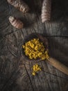 Turmeric powder and rhizome on wooden ladle. Overhead of vintage wooden table