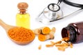 Turmeric powder, tumeric herbal capsules, curcuma root and glass bottle of turmeric extract essential oil with medical stethoscope