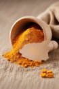 Turmeric powder in a wooden mortar on burlap background