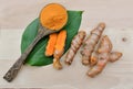 Turmeric powder in a wooden spoon on the leaves of turmeric root; herb for health and high vitamin c.itamin C for protect virus Royalty Free Stock Photo