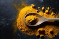 Turmeric powder in wooden spoon over dark background.