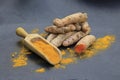 Turmeric powder in a wooden spoon and roots on a dark table curcuma longa, Kurkuma