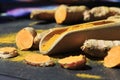 Turmeric powder in a wooden spoon and roots on a dark table curcuma longa, Kurkuma