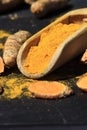 Turmeric powder in a wooden spoon and roots on a dark table curcuma longa, Kurkuma