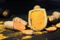 Turmeric powder in a wooden spoon and roots on a dark table curcuma longa, Kurkuma