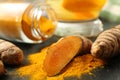 Turmeric roots, powder and cup of tasty tea on black table, closeup Royalty Free Stock Photo
