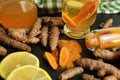 Turmeric roots, powder, sliced lemon and cup of tasty tea on black table Royalty Free Stock Photo