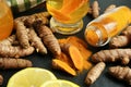 Turmeric roots, powder, sliced lemon and cup of tasty tea on black textured table, closeup Royalty Free Stock Photo