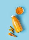 Turmeric smoothie in glass bottle with ingredients, turmeric powder on blue background Royalty Free Stock Photo