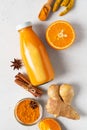 Turmeric smoothie in glass bottle with ingredients, turmeric powder, ginger and spice on white or light grey background Royalty Free Stock Photo