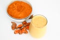 Turmeric smoothie and turmeric powder in bowl with pieces of turmeric root isolated on white