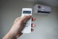 Turn on the air conditioner at 26 degrees Celsius. Hand holding the air conditioner remote control and thumb is pressing a button Royalty Free Stock Photo