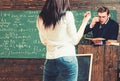 Turn back brunette girl in front of professor. Strict teacher looking at his female student while standing at rostrum Royalty Free Stock Photo