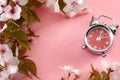Turn clocks on hour ahead, star of daylight savings time and reminder to spring forward concept with alarm clock on pink