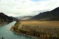 A turn in the course of a wide turquoise river flowing through a huge valley in the mountains on a cloudy autumn day Royalty Free Stock Photo